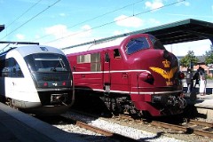 DSB Museumstog MX 1001 photographed in Odense beside DSB MQ 4111.14. August 2004.  The MX class was built by Nydquist & Holm AB (NOHAB) in Sweden licensed by General Motors. It was based on the MY class, but was built with a lower axle load for the Danish branch lines. The MX class was put in service in 1960 - 1962. A1A-A1A. Dieselelectric. 1.445 hp. Max speed 133 km/h - 83 mph. Length 18 300 mm. Weight 89 metric tonnes. Built in a number of 45. MX 1001 was put in service in 1960. Withdrawn from service in 1988 and taken over by the DSB Museumstog. Photographed in Odense during the railwaymuseum's 50th aniversary celebration of the first My class (from General Motors) being put in service in Denmark.